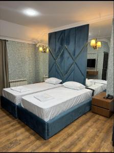 a bedroom with a large bed with a blue headboard at Buta Hotel Berde in Bǝrdǝ