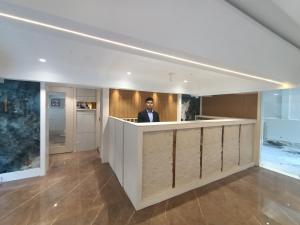 a man is standing behind a counter in a lobby at Hotel Pearl Residency in Thane