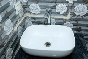 lavabo blanco en un baño con flores en la pared en Charlie's Hostel By Purple India en Nueva Delhi