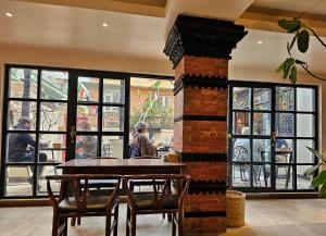 comedor con mesa, sillas y ventanas en SWARGA HERITAGE HOTEL - A TRADITIONAL STAY, en Katmandú