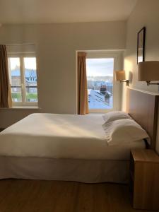 ein Schlafzimmer mit einem großen weißen Bett und einem Fenster in der Unterkunft Le Grand Hôtel Ussel ''nouvelle Gérance 2023'' in Ussel