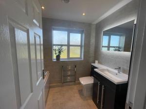 La salle de bains est pourvue d'un lavabo, de toilettes et d'une fenêtre. dans l'établissement Large Lytham Home - The Birds View by Holiday Heim, à Lytham St Annes