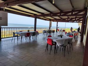 una sala da pranzo con tavoli, sedie e vista sull'oceano di HOTEL DE L'OCEAN KRIBI a Kribi