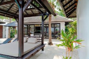 an outdoor patio with a bed and an umbrella at Privatbeach residences villa 29 in Koh Samui 
