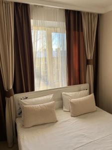 uma cama com almofadas brancas em frente a uma janela em люкс квартира в центре города - все удобства - ждем Вас! em Karaganda
