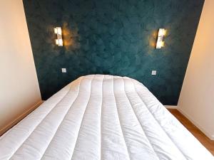 1 cama en un dormitorio con 2 luces en la pared en Appartement au centre de TREBEURDEN et à 400m de la plage - Réf 662, en Trébeurden