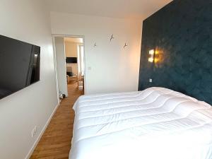 1 dormitorio con 1 cama blanca y TV de pantalla plana en Appartement au centre de TREBEURDEN et à 400m de la plage - Réf 662, en Trébeurden