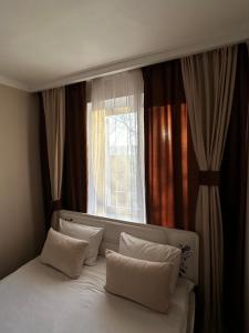 1 cama con almohadas blancas frente a una ventana en люкс квартира в центре города - все удобства - ждем Вас!, en Karagandá