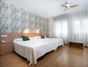 a bedroom with a large white bed and a ceiling fan at Hotel Mi Casa in Sabiñánigo