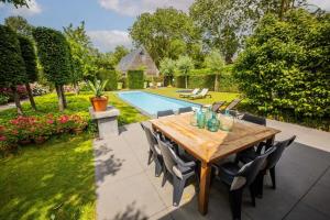 un patio con mesa de madera y sillas junto a una piscina en Fabulous 4 Bedroom Villa (KS-10), en Eindhoven