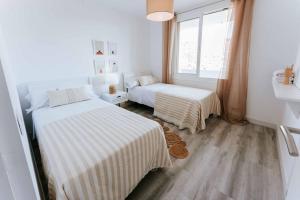 Cette chambre blanche dispose de deux lits et d'une fenêtre. dans l'établissement Apartamento balcón del Mar, à Almería