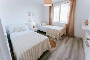 a white room with two beds and a window at Apartamento balcón del Mar in Almería
