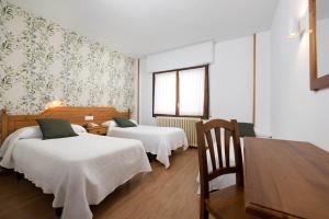 ein Hotelzimmer mit zwei Betten und einem Tisch in der Unterkunft Hotel Mi Casa in Sabiñánigo