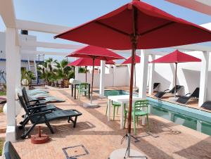 un groupe de tables et de parasols à côté d'une piscine dans l'établissement Riad Ocean Beach Douira, à Agadir