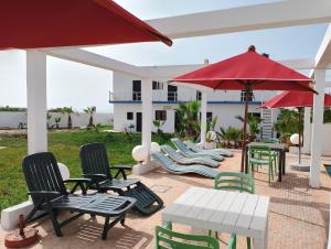 un patio con sedie, tavoli e ombrellone rosso di Riad Ocean Beach Douira ad Agadir