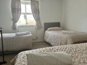1 dormitorio con 2 camas y ventana en Bluebell House 2 bedroom with parking and garden en Scunthorpe
