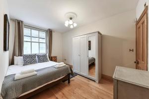 1 dormitorio con cama y ventana grande en Knightsbridge 2BR Mews House, en Londres