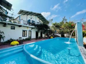 a pool with a water fountain in front of a house at An An Homestay Bungalow in Phong Nha