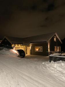 a house with a car parked in the snow at night at Hus i landlige omgivelser nær Granåsen skianlegg in Trondheim