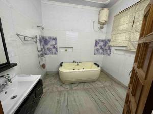 a white bathroom with a tub and a sink at Anand Nilaya (2.5 km from Sukhna Lake, Chd) in Chandīgarh