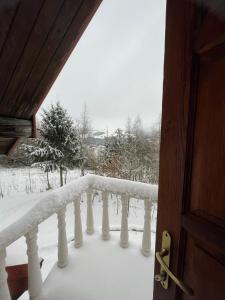 d'un balcon recouvert de neige avec une balustrade. dans l'établissement Magurska enklawa- domek letniskowy, à Nowy Żmigród