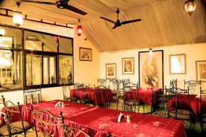 a room with tables and chairs with red table cloth at Haveli Expedition & Resort in Ghānerao