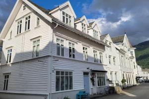 een wit gebouw met witte ramen op een straat bij Sjarmerande hus i Eidsgata in Nordfjordeid
