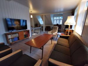 ein Wohnzimmer mit einem Sofa, einem Tisch und einem TV in der Unterkunft Sjarmerande hus i Eidsgata in Nordfjordeid