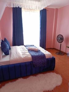 1 dormitorio con 1 cama con cortinas azules y ventana en JABALI's Homestay, en Kisumu