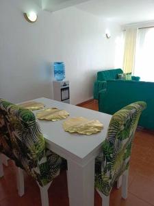 mesa blanca con 2 sillas, mesa y sofá en JABALI's Homestay, en Kisumu