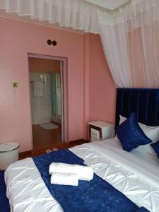 1 dormitorio con 1 cama con toallas en JABALI's Homestay, en Kisumu