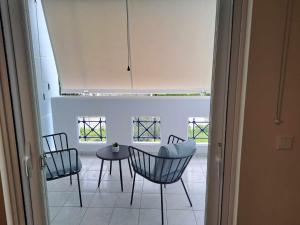 a room with chairs and a table and windows at Spata Airside Apartment in Spata +2 photos
