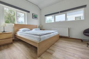 1 dormitorio con 1 cama grande y 2 ventanas en Túngata apartment en Seyðisfjörður