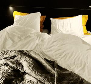 un letto non preparato con lenzuola e cuscini bianchi di B&B en Vakantiewoningen 't Wienhoes a Wittem