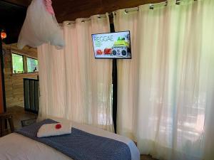 een slaapkamer met een bed en een bord met een camera bij Eco Cabana a 150 metros da praia e centrinho in Paraty