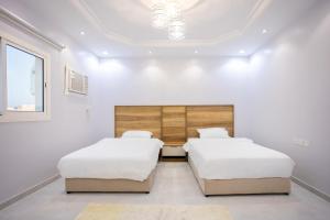 Duas camas num quarto com paredes brancas em أجنحة لفيف 1 em Al Madinah