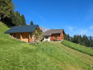 una cabaña de madera en una colina con un campo verde en Berghaus Kessler, en Vandans