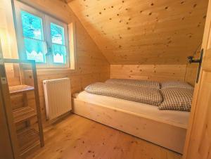 a bed in a wooden cabin with a window at Berghaus Kessler in Vandans