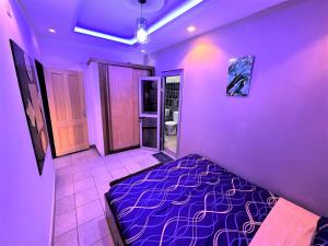 a purple room with a bed and a bathroom at The Yafé Bastos 17 in Yaoundé