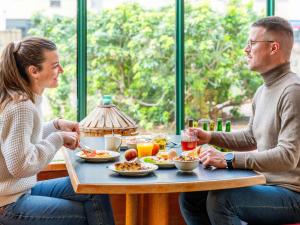 un hombre y una mujer sentados en una mesa comiendo comida en ibis Lyon Gare Part Dieu en Lyon