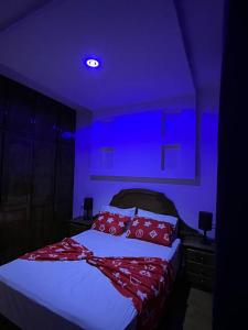 Schlafzimmer mit einem Bett mit roten Kissen und lila Beleuchtung in der Unterkunft Appartement pour famille à Agadir 10 minutes de la plage Parking gratuit in Agadir