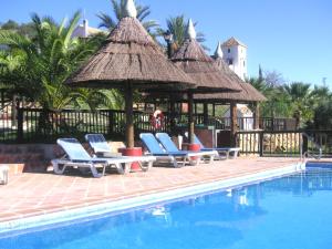 a pool with chairs and a gazebo next to a resort at Castle Tower apartment in rural holiday park 'Bernard' in Tolox