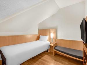 a small bedroom with a bed and a tv at Ibis Budapest Heroes Square in Budapest