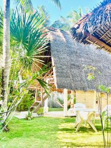 a house with a thatched roof with a bench in the yard at Boholala hostel in Panglao Island