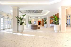 a lobby with plants in large white pots at Embassy Suites by Hilton Deerfield Beach Resort & Spa in Deerfield Beach