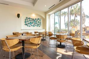 ディアフィールドビーチにあるEmbassy Suites by Hilton Deerfield Beach Resort & Spaのテーブルと椅子、大きな窓のあるレストラン