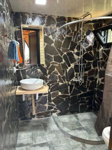 Baño de piedra con lavabo y espejo en HillSide Cottage en K'eda