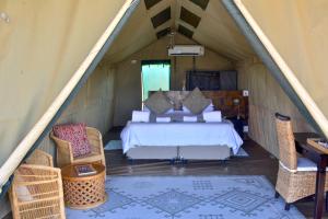a bedroom in a tent with a bed and chairs at Mopane Bush Lodge in Linton