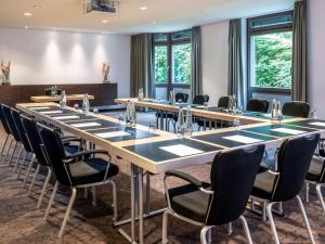 uma sala de conferências com uma mesa longa e cadeiras em Mövenpick Hotel München-Airport em Hallbergmoos