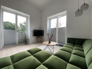 a living room with a green couch and two windows at ApartmentInCopenhagen Apartment 1460 in Copenhagen